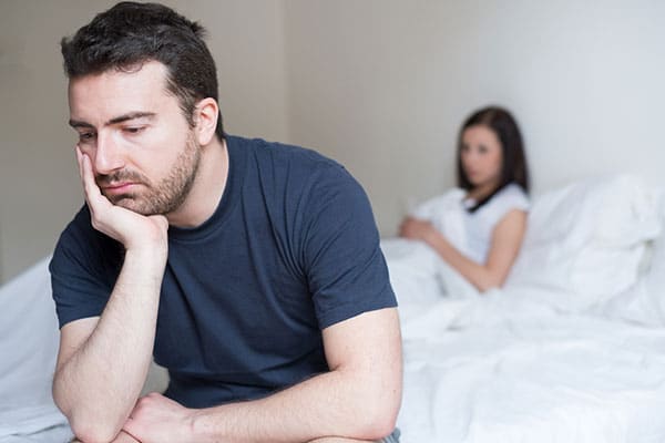 Photo of couple sitting on a bed.