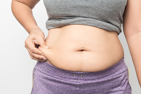 Photo of woman pinching her belly fat.