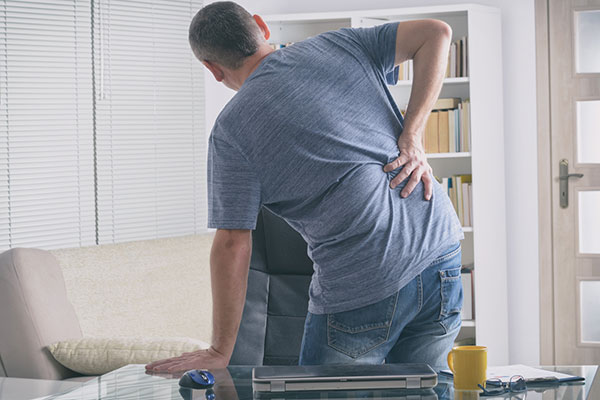 Photo of man holding back in pain.