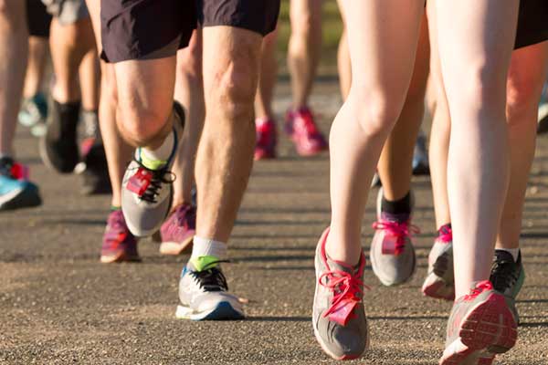 Image of many peoples legs in tennis shoes running in a group.