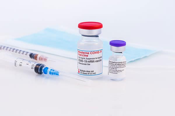Syringes lay next to bottles of corona virus vaccines.