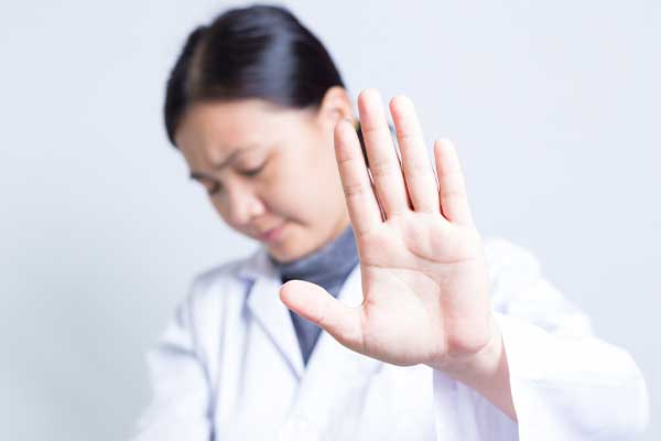 Female Doctor holding hand out to camera in a stopping symbol.