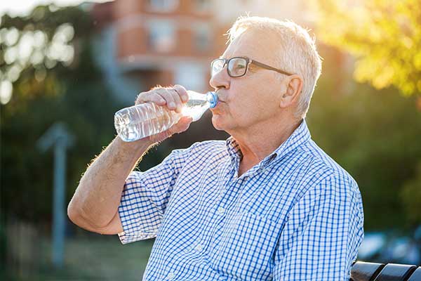 Man Sitting outside drinking a beverage.