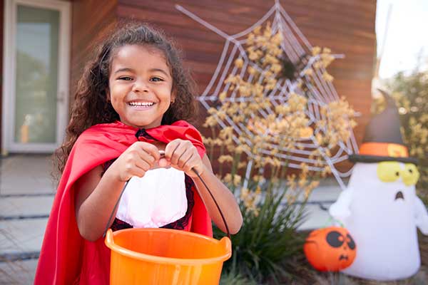 LIttle girl smiling holding bucket of halloween candy.