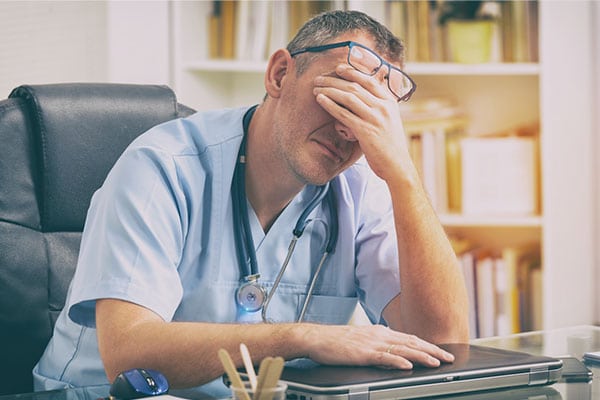 Doctor sitting tired at a desk.