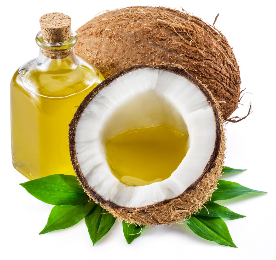 A bottle of Coconut oil next to a cut in half coconut.