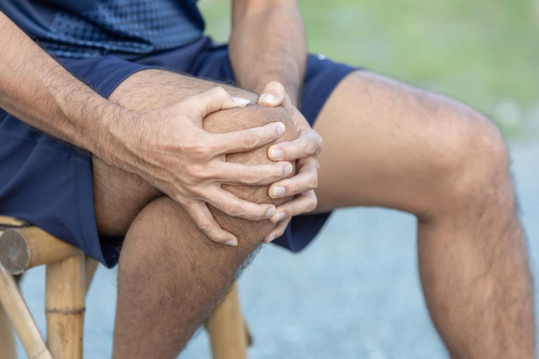 Man holding knee in discomfort.