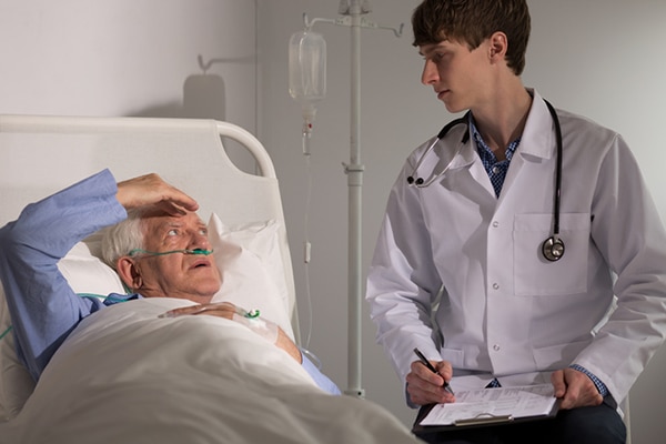 Image of man in hospital bed heading his head.